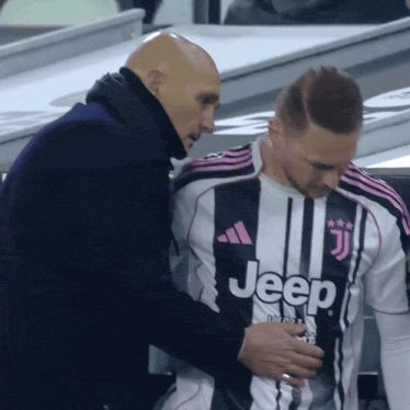 a man in a black and white jeep shirt is being comforted by another man